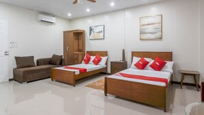 A hotel room with two beds, a wardrobe, a sofa, a ceiling fan, and artwork on the walls. - OYO 805 La Belladoza (Parañaque)