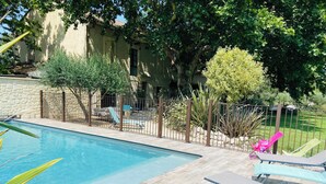 A swimming pool with a wooden deck, lounge chairs, and a stone wall. - 18th century gite mas in Provence with SPA (chateaurenard)