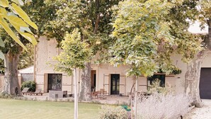 A building with a garden area, outdoor seating, and a tree in front. - 18th century gite mas in Provence with SPA (chateaurenard)