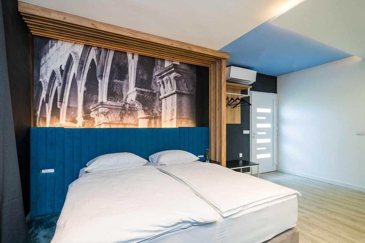 Une pièce comprenant un lit, une grande œuvre d’art accrochée au mur, une armoire et une porte dotée d’une poignée.