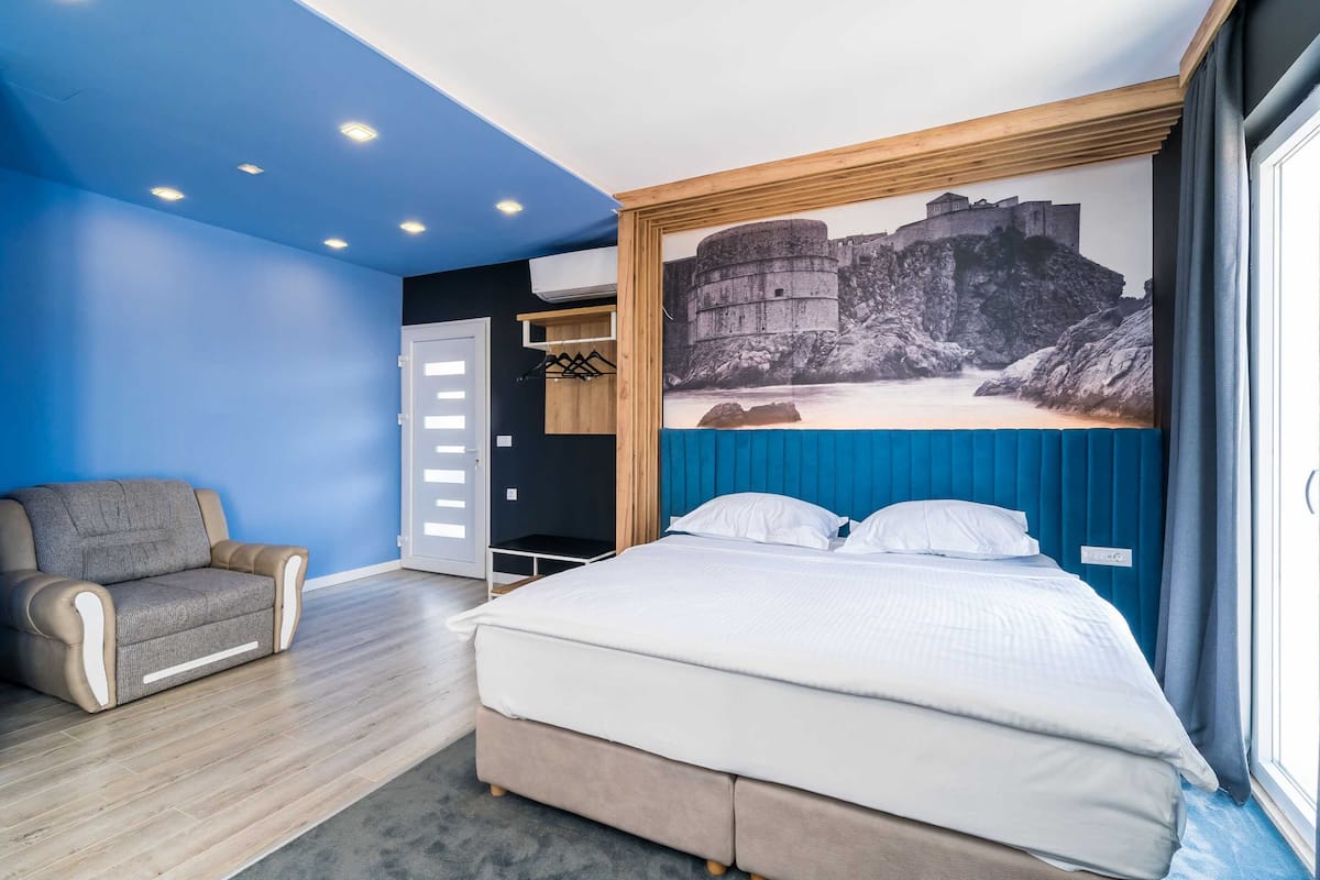 Une chambre à coucher comprenant un lit, une chaise, une armoire et une fresque représentant un château sur le mur.
