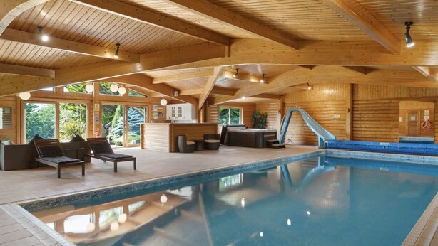 A wooden interior with a pool, lounge area, and hot tub.