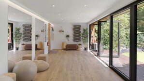 A spacious interior with a wooden floor, a large sliding glass door leading to an outdoor area, and a wall-mounted shelf with decorative items.