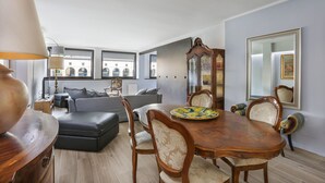 A dining area with a wooden table, chairs, and a decorative plate. There is a sofa and a lamp in the background. - Stunning view over Ponte Vecchio (Firenze)