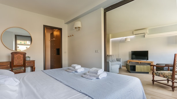A hotel room with a large bed, a wooden chair, a television, and a mirror. - Stunning view over Ponte Vecchio (Firenze)