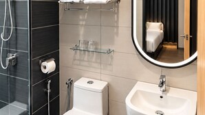 Ein modernes Badezimmer mit Toilette, Bidet, Dusche und Waschbecken.
