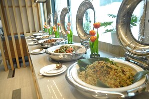 Un buffet proposant divers plats, agrémenté d’une composition décorative de tulipes.