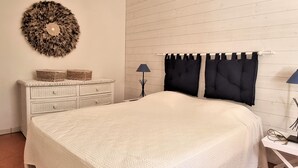 A bedroom with a large bed, a dresser, a round wall decoration, and two lamps. - Mediterranean F4 Villa with Direct Cove Access and Parking (Banyuls-sur-Mer)