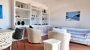 A modern living room with a white sofa, a dining table, and a white cabinet with shelves. - Mediterranean F4 Villa with Direct Cove Access and Parking (Banyuls-sur-Mer)