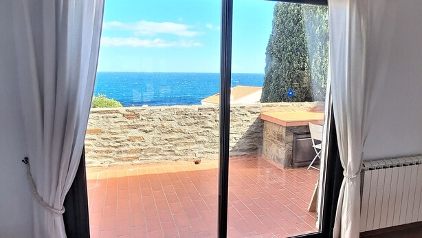 A room with a large sliding glass door leading to a terrace with a view of the sea and rocky terrain. - Mediterranean F4 Villa with Direct Cove Access and Parking (Banyuls-sur-Mer)