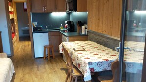A compact kitchen with wooden cabinets, a small island, and a dining table with chairs. - Newly renovated apartment. It is located 150 metres from the slopes, opposite the comm (Montvalezan)