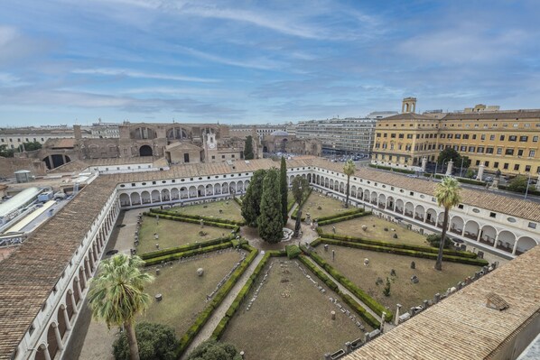 A courtyard with a central fountain, surrounded by a colonnade and palm trees. - Camplus Hotel Roma Centro (Rome)