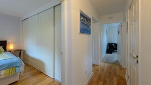 Ein Hotelzimmer mit Bett, Nachttisch, Schrank und einem zur anderen Kammer führenden Flur.
