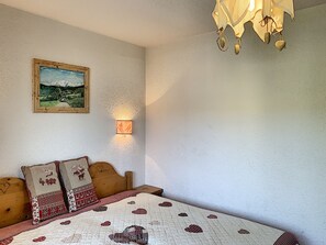 Un dormitorio con una cama, una mesita de noche, una lámpara de pared y un cuadro enmarcado.