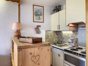 Una cocina compacta con encimera de madera, estufa, fregadero y cafetera.