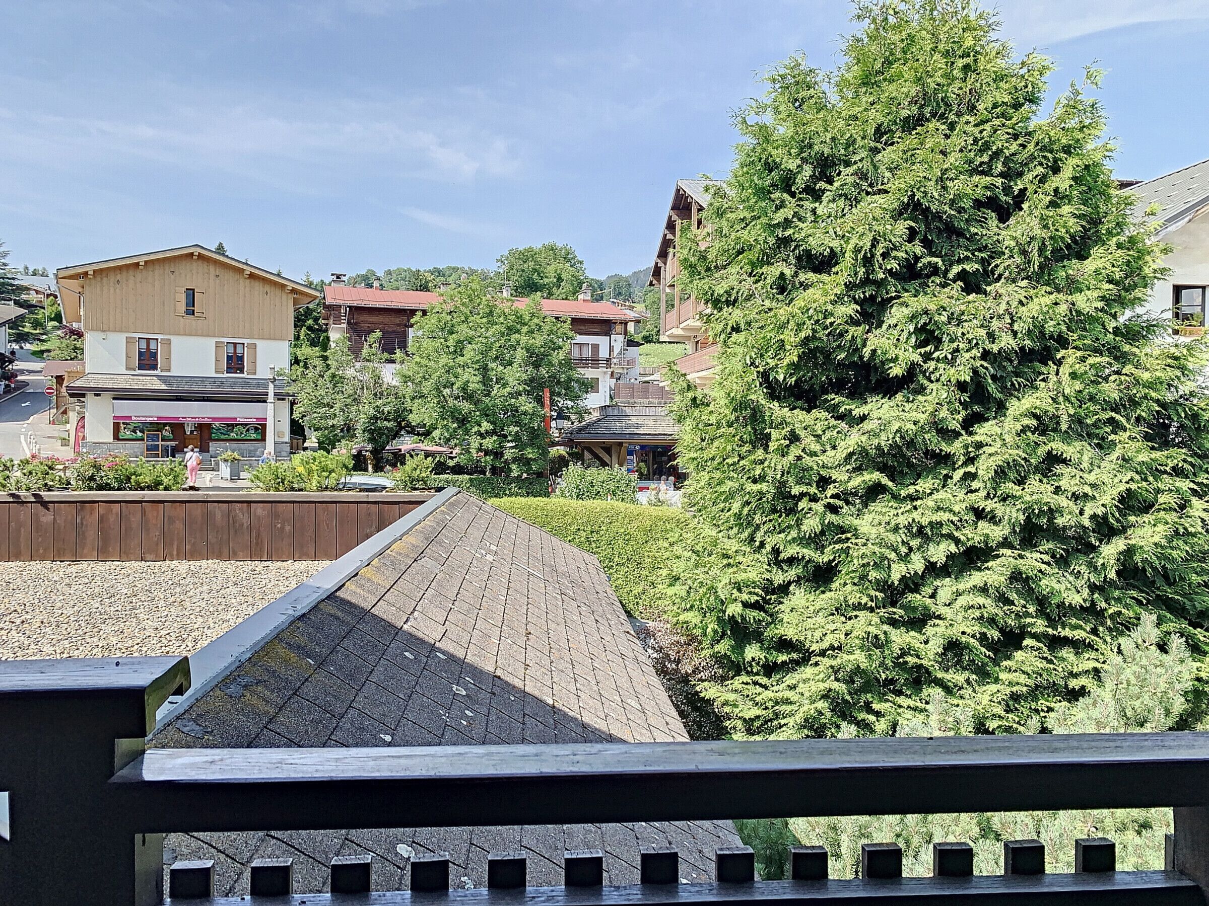 A view of a town with buildings, a paved area, and a large tree.