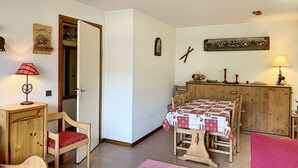 Un salon chaleureux avec une table en bois, des chaises, un canapé et une porte donnant sur une autre pièce.