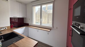 A modern kitchen with a built-in oven, a window with a view of the outside, and a wooden countertop. - Charming City Center House with Beach Access, Free WiFi, Garage, Baby Gear, & Renovated Interiors (Les Sables-d'Olonne)