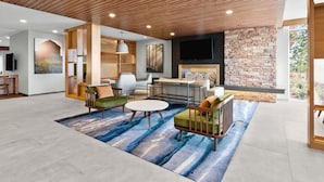 A modern living room with a fireplace, wooden ceiling, and a large TV.