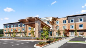 A multi-story hotel with a covered entrance, outdoor landscaping, and a clear blue sky.