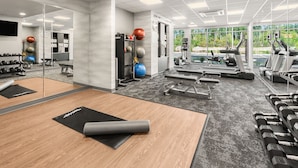 A gym with exercise equipment, a mirror, and a view of the outdoors.