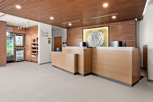 A reception area with wooden reception desks, a refrigerated display case, and a wall-mounted decorative piece.