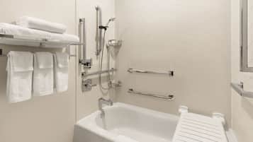 A modern bathroom with a bathtub, shower, and handrails.