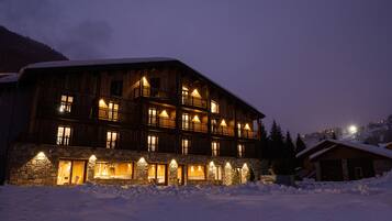 Ein mehrstöckiges Holzhaus mit Balkonen und Steinfundamenten, umgeben von Schnee.