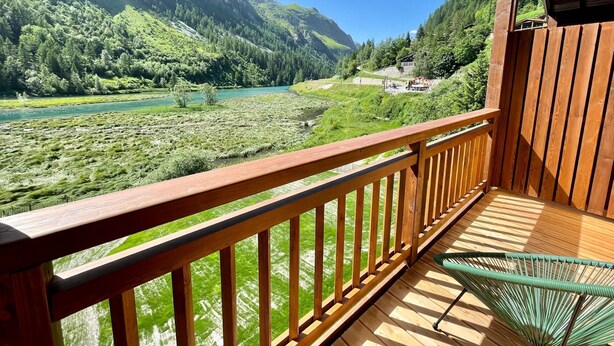 Eine Holzterrasse mit Blick auf einen Fluss und Berge.