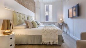 A bedroom with a bed, bedside lamp, and a TV on the wall. - GuestHost - Ferrara Torre dei Leuti White Apartment (Ferrara)