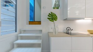 A modern kitchen with white cabinets, a wooden countertop, a kettle, and a plant. - GuestHost - Ferrara Torre dei Leuti White Apartment (Ferrara)