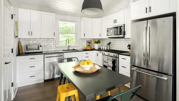 A modern kitchen with white cabinets, stainless steel appliances, and a central island with a bowl of lemons. - Treefort (Atlanta)