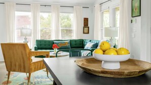 A room with a wooden dining table, a green sofa, and a bowl of lemons on a wooden tray. - Treefort (Atlanta)