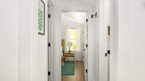 A hallway with white walls, a wooden floor, and a green rug. - Treefort (Atlanta)