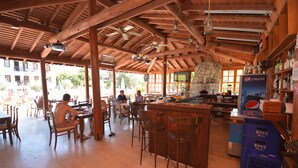 Un coin bar en bois avec des tabourets, un comptoir et un réfrigérateur à boissons Pepsi.