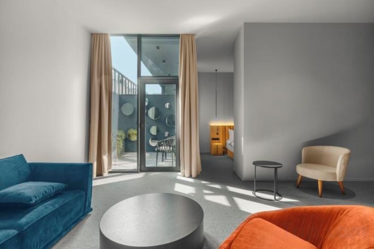 A modern living room with a sofa, armchair, and round coffee table.