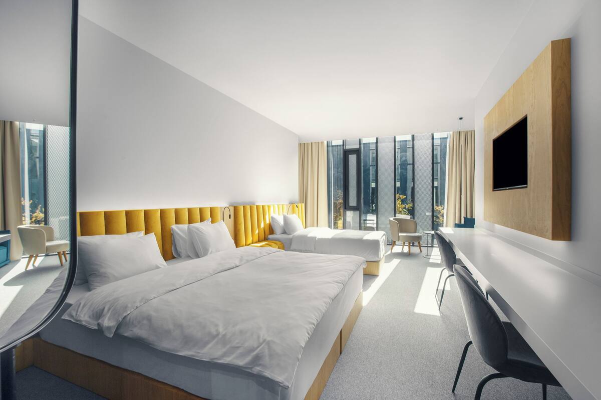 A modern hotel room with a large bed, a desk, and a TV.