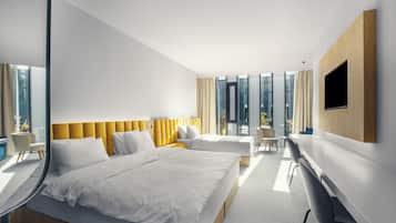 A modern hotel room with a large bed, a desk, and a TV.
