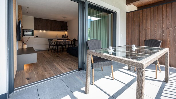 Eine moderne Küche mit Holzausstattung und einem Essbereich mit Glastisch und Korbstühlen.
