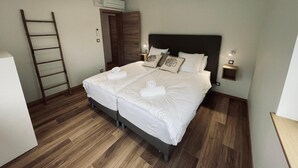 A neatly made double bed with white linens, two bedside tables with lamps, a wooden ladder, and a wooden wardrobe. - 3-room gîte with terrace (Wintzenheim)