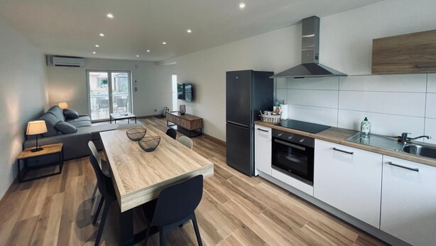 A modern kitchen with a wooden dining table, black chairs, and a built-in oven. - 3-room gîte with terrace (Wintzenheim)