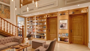 A spacious library with wooden bookshelves, a comfortable seating area, and a staircase leading to an upper level.