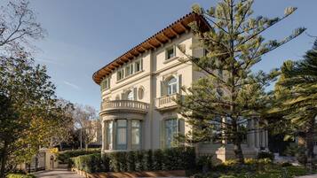 Un grand bâtiment historique à la façade incurvée, doté de nombreuses fenêtres et d’un balcon imposant.