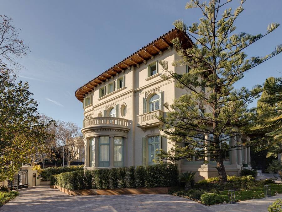 A large, historic building with a curved facade, multiple windows, and a prominent balcony.