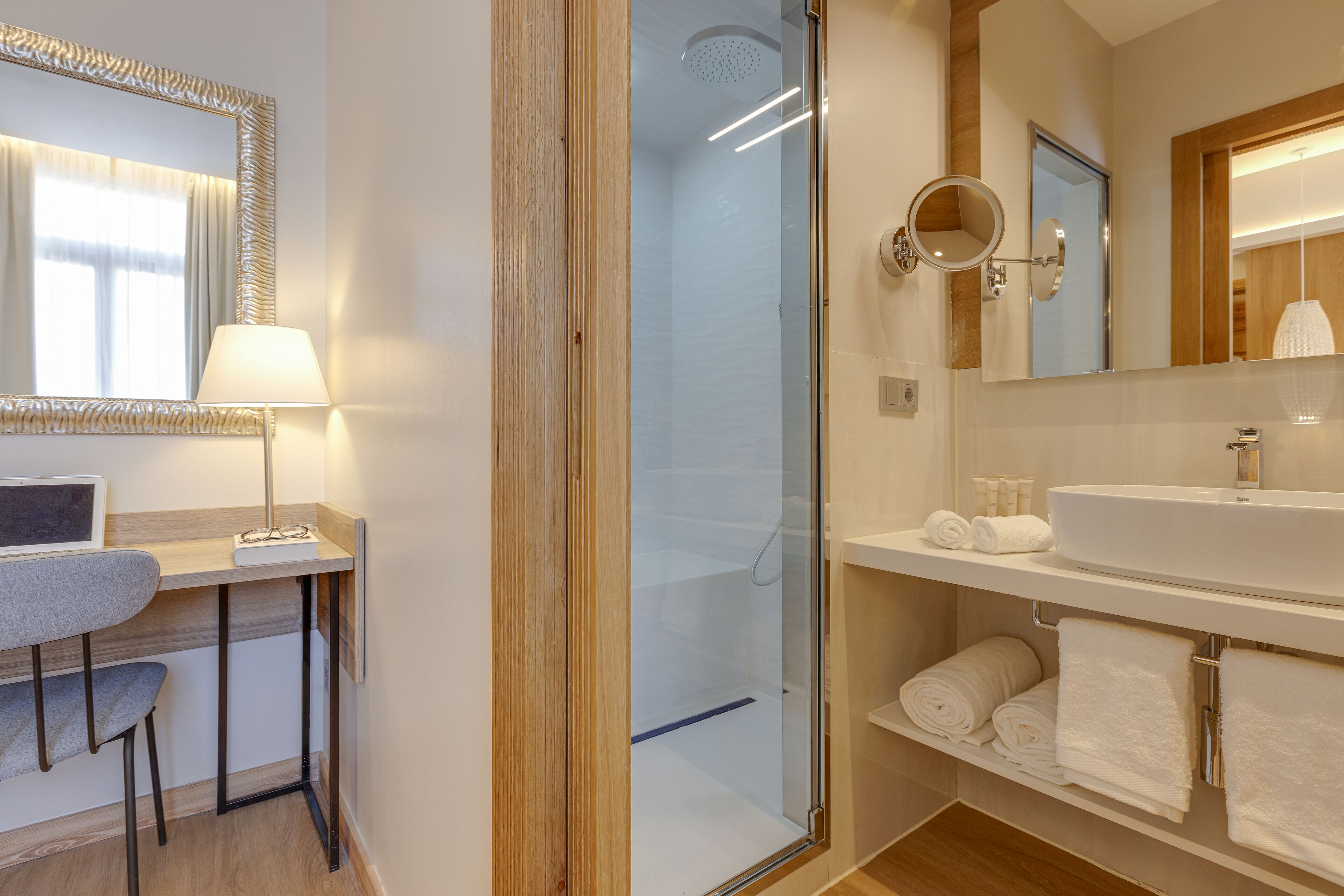 A modern bathroom with a glass shower enclosure, a vanity with a large mirror, and neatly arranged towels.
