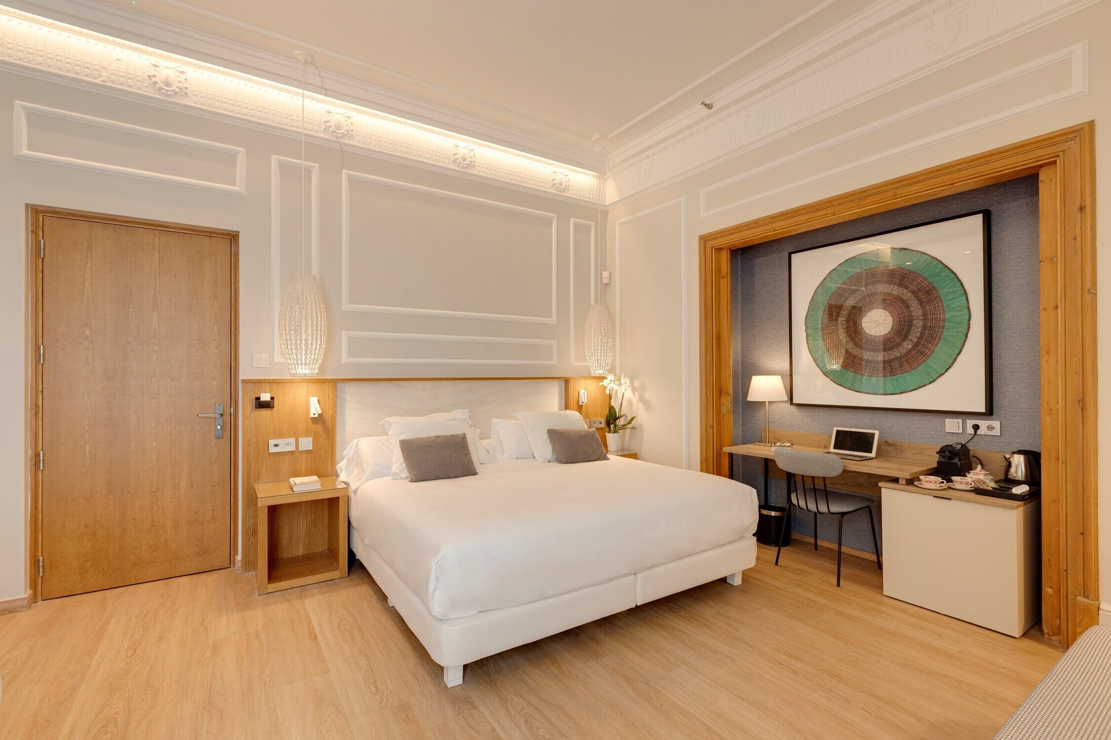 Een hotelkamer met een groot bed, een bureau en een kleine kitchenette.