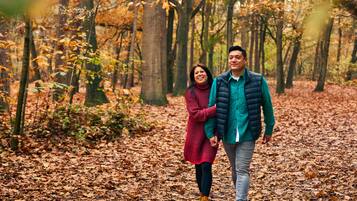 Una pareja caminando por un sendero cubierto de hojas en un bosque.