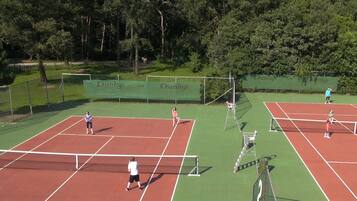En tennisbane med flere baner, et net og et hegn.
