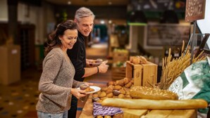 Een bakkerijvitrine met verschillende broden en gebak.