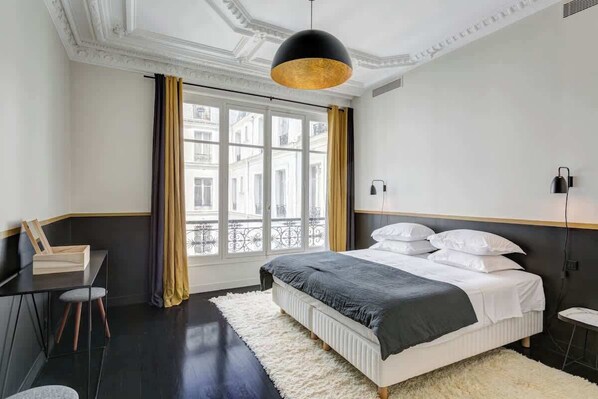 A modern bedroom with a large bed, a desk, and a chair.